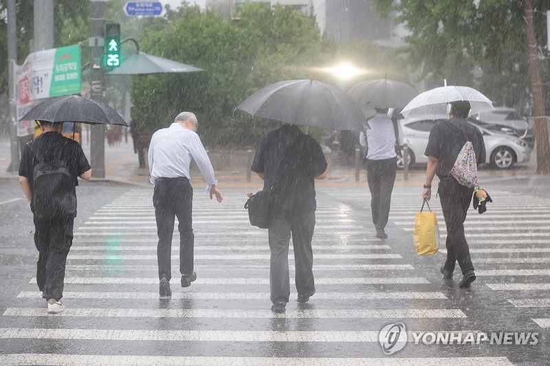 8일 서울 영등포구 여의도 국회 인근에서 시민들이 우산을 쓰고 이동하고 있다 / 연합뉴스